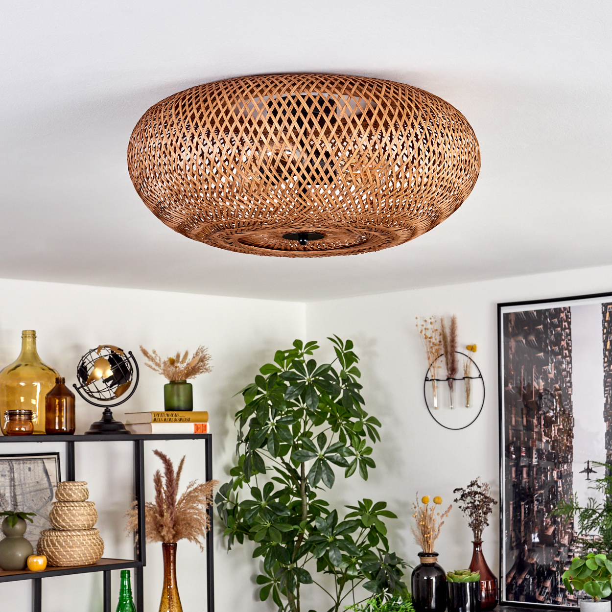 Eine Deckenlampe aus geflochtenem Rattan. Darunter Regale mit Vasen, einem Globus und Pflanzen. Auf der rechten Seite eine große Pflanze.