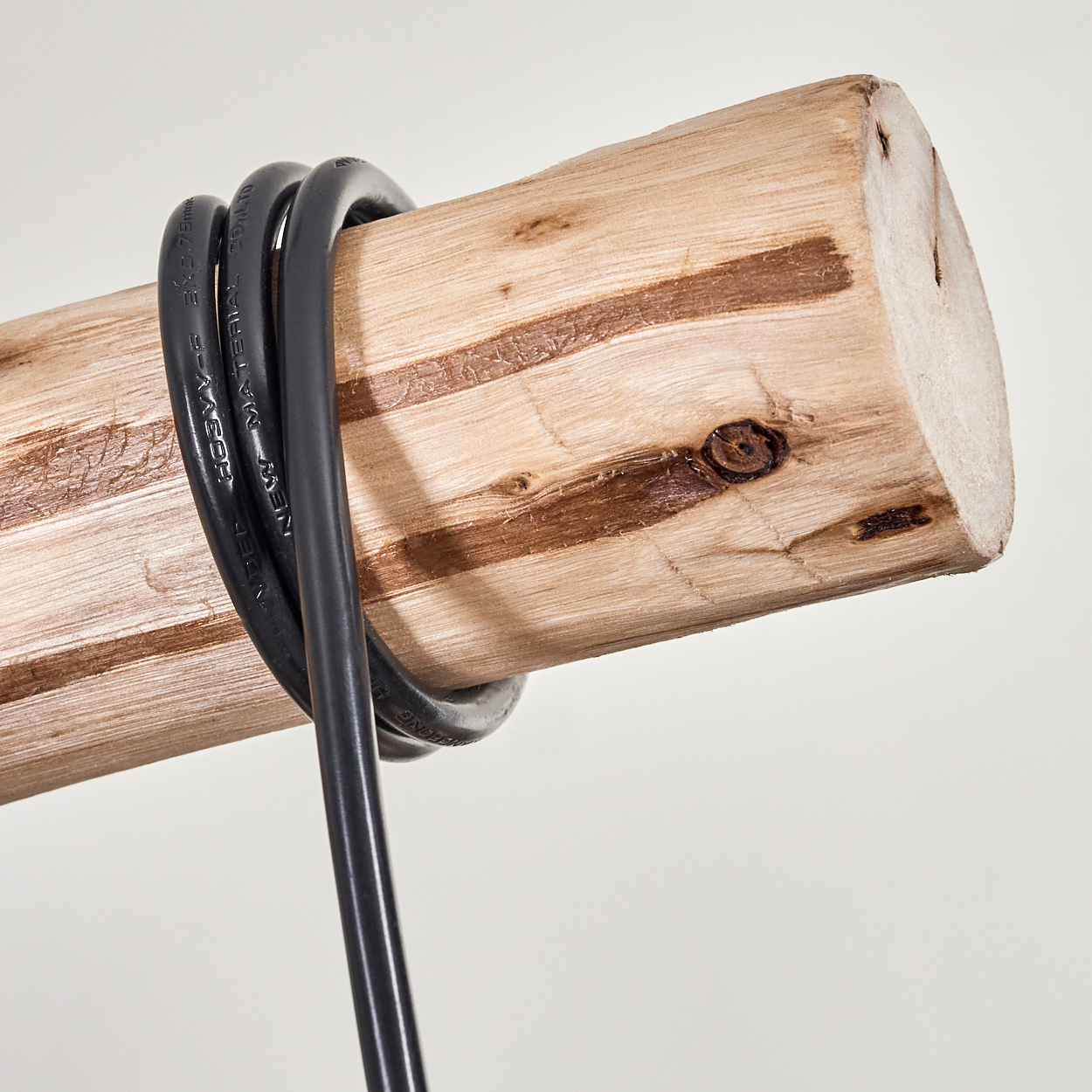 Ein schwarzes Kabel ist um einen Holzstamm gewickelt. Der Stamm ist hellbraun mit dunkelbraunen Streifen und Ästen. Der Hintergrund ist weiß.