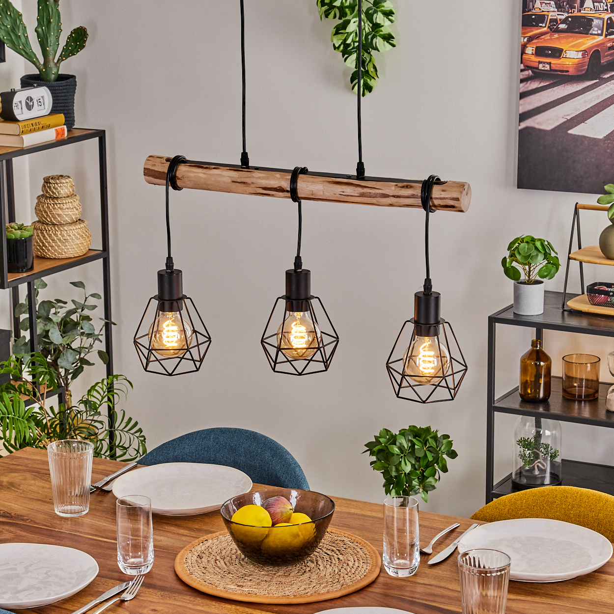 Esszimmer-Szene. Holztisch mit Tellern, Gläsern und einer Obstschale unter einer dreifachen Pendelleuchte. Hintergrund mit Regalen und Pflanzen.