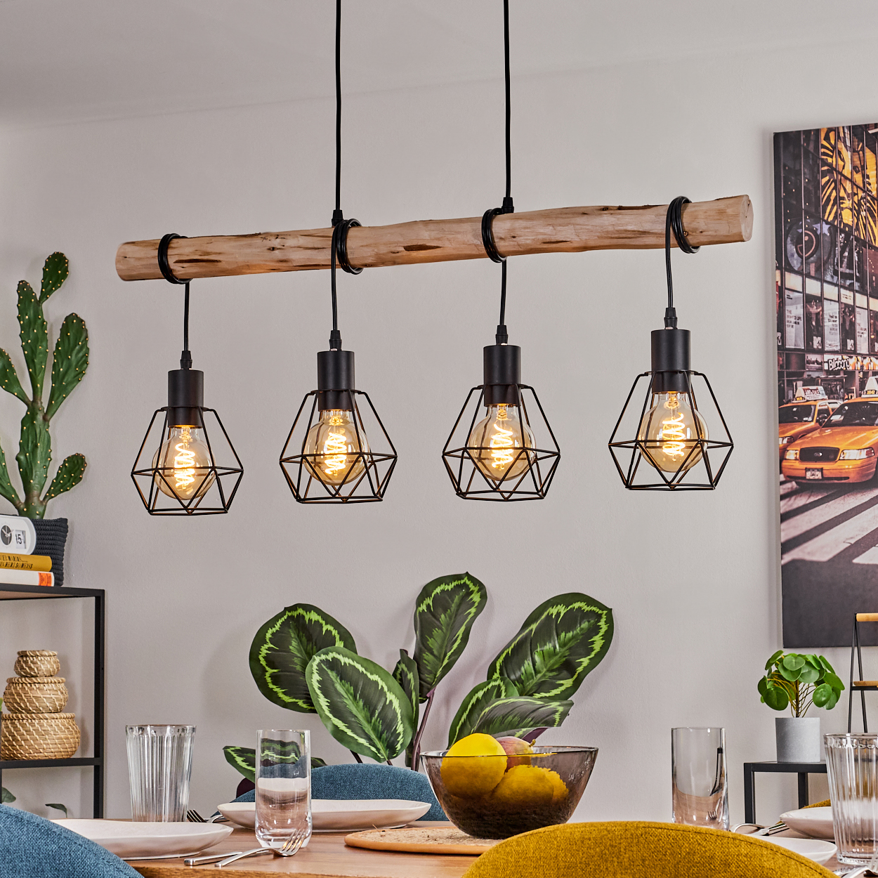Ein Esszimmer mit einem Holzbalken-Kronleuchter mit vier schwarzen geometrischen Lampen. Ein Tisch mit Tellern, Gläsern und Pflanzen ist zu sehen.