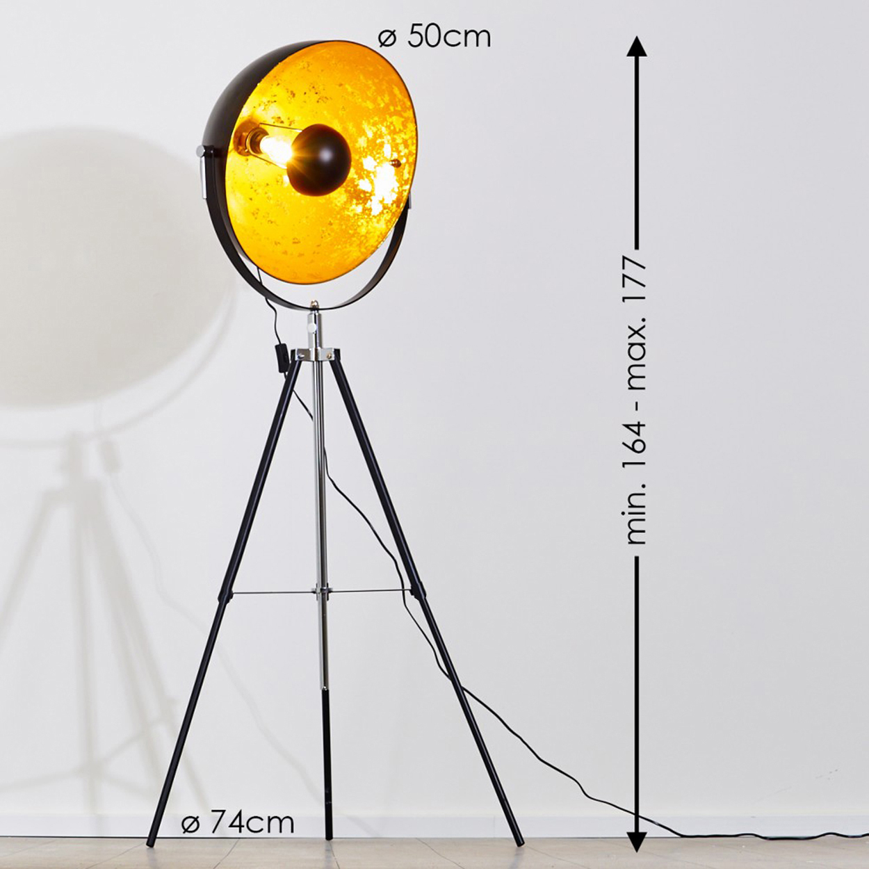 Eine schwarz-goldene Stehlampe mit Dreibein-Fuß. Die Lampe ist 164-177 cm hoch und hat einen Durchmesser von 50 cm.