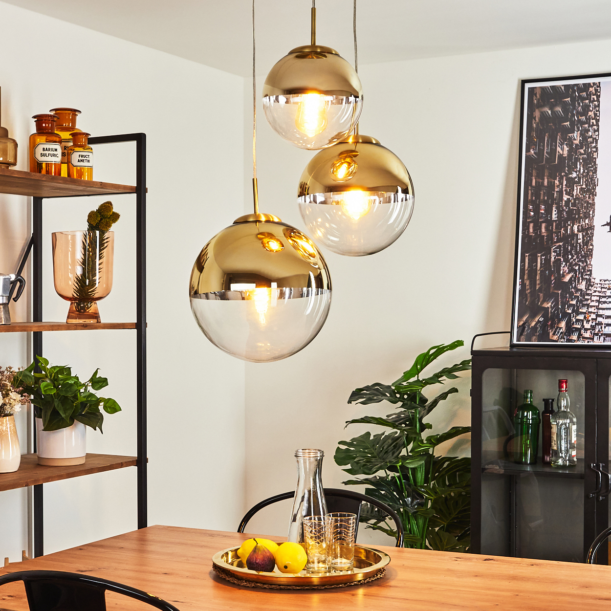 Esszimmer mit Hängelampen, Tisch mit Obst- und Gläsertablett, Pflanzen und einem Schrank mit Flaschen.