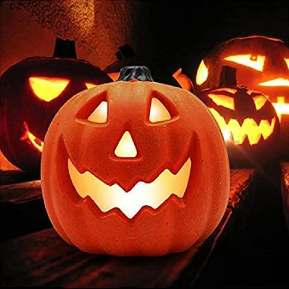 Oranger Kürbis mit geschnitztem Gesicht, von innen beleuchtet. Mehrere andere Kürbisse mit leuchtenden Gesichtern im Hintergrund, eine Halloween-Szene.