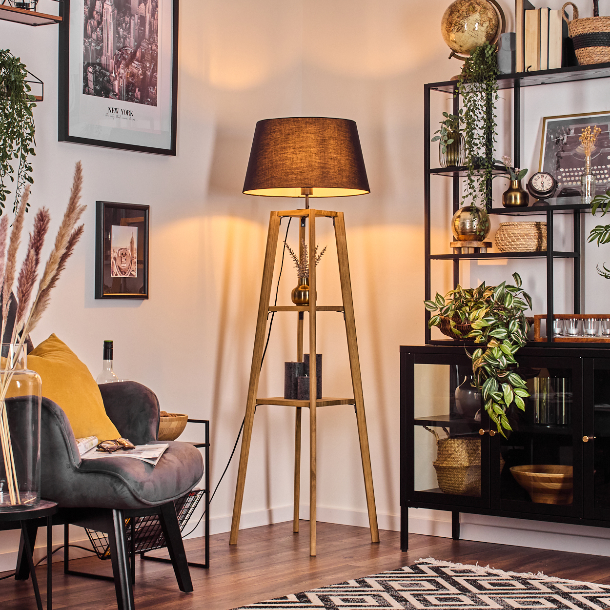 Eine Zimmerecke mit Holzlampe, schwarzem Schrank und Metallregal mit Deko. Links ein Stuhl mit gelbem Kissen.