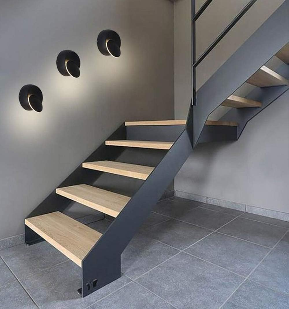 Moderne Treppe mit Holzstufen. Schwarzer Metallrahmen mit drei Wandlampen. Graue Wände und Boden.