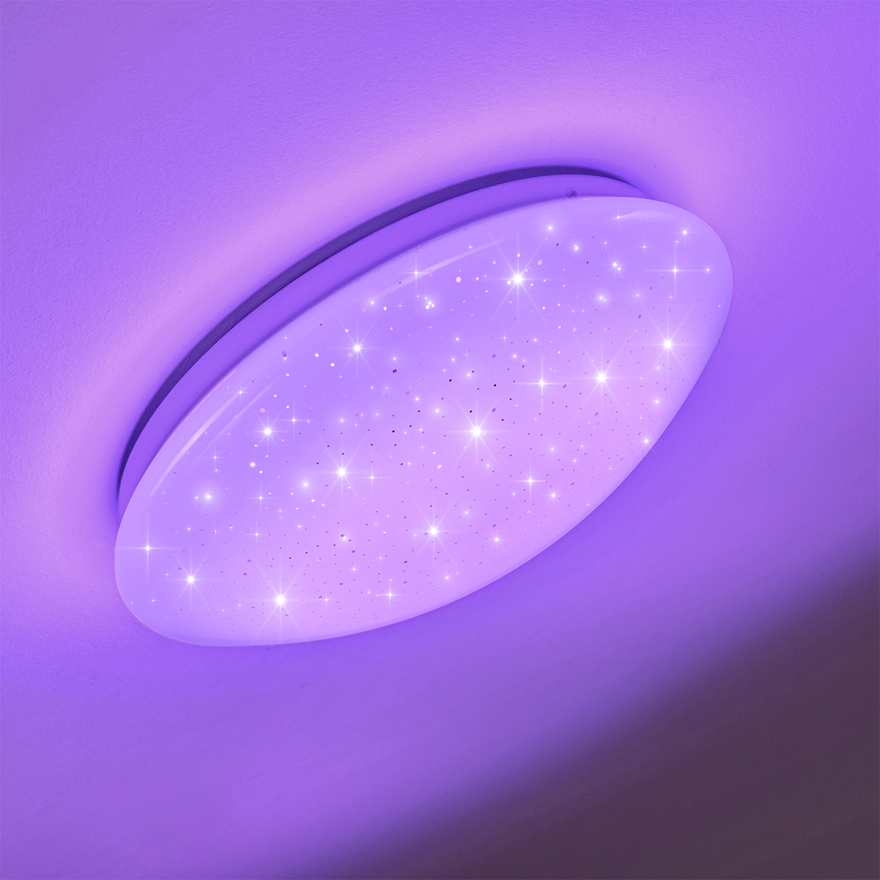 Eine weiße, ovale Deckenleuchte mit funkelnden sternartigen Lichtern an einer lila Decke. Das Licht ist leicht angewinkelt.