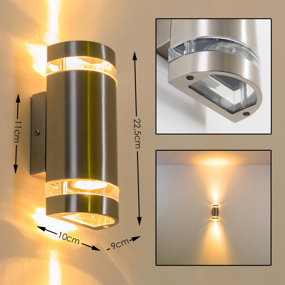 Eine Wandleuchte für den Außenbereich aus gebürstetem Metall. Die Leuchte hat eine zylindrische Form mit klaren Lichtdiffusoren.