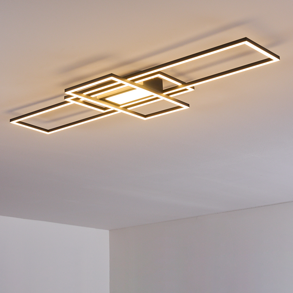 Eine moderne Deckenleuchte mit geometrischen Formen. Sie besteht aus schwarzem Metall und hat leuchtende weiße LED-Streifen.