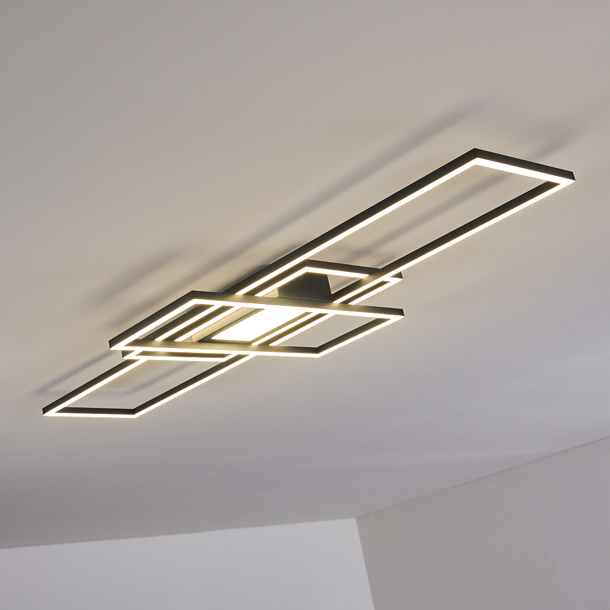 Moderne Deckenleuchte mit quadratischen Rahmen und hellen weißen LEDs. Hintergrund ist eine weiße Decke.
