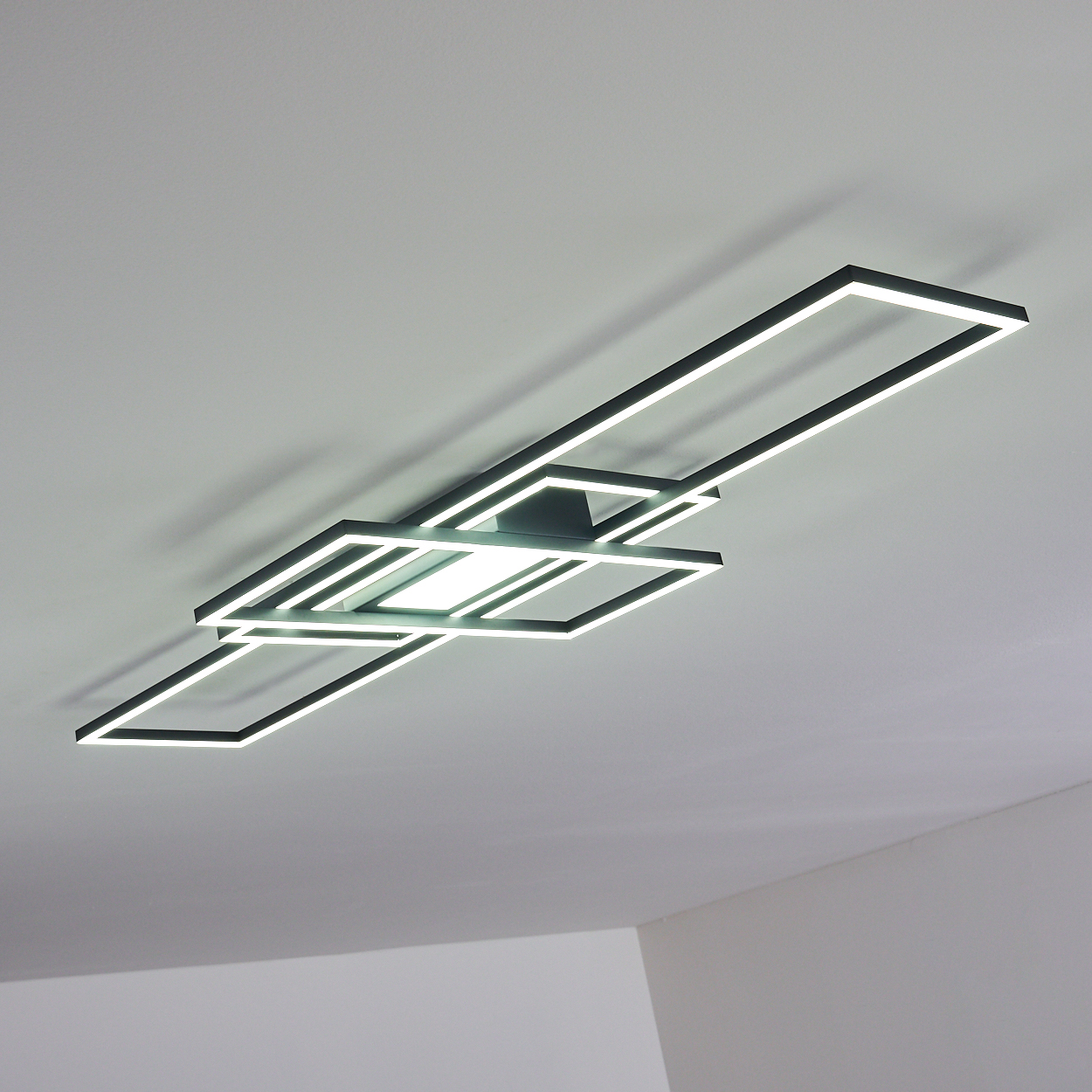 Eine moderne Deckenleuchte. Sie hat einen schwarzen Rahmen mit hellweißen Lichtern. Das Licht hat ein quadratisches und rechteckiges Design.
