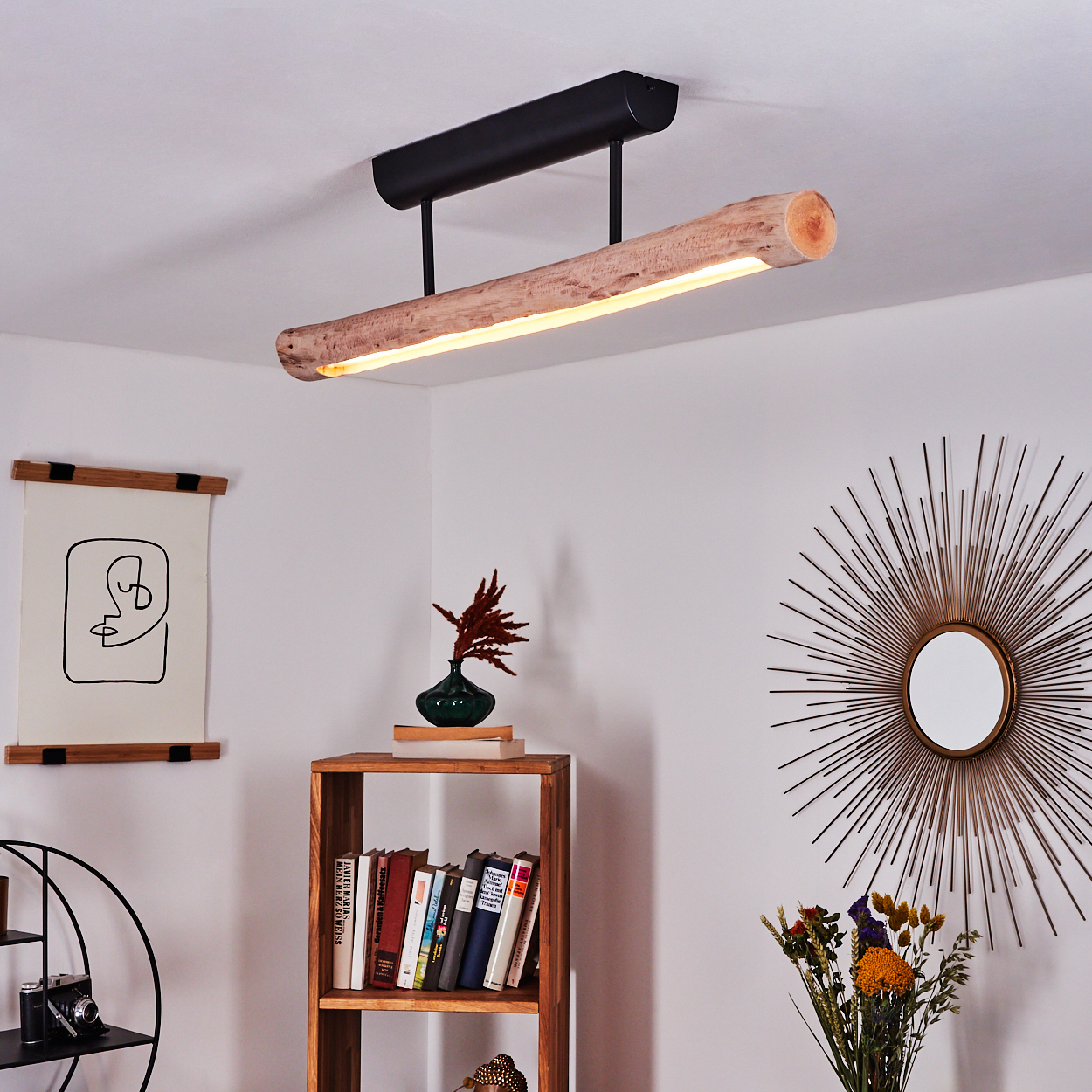 Ein modernes Zimmer mit einer Deckenleuchte aus Holz, einem Bücherregal, einem Spiegel und einer Vase mit Blumen. Die Wände sind weiß.
