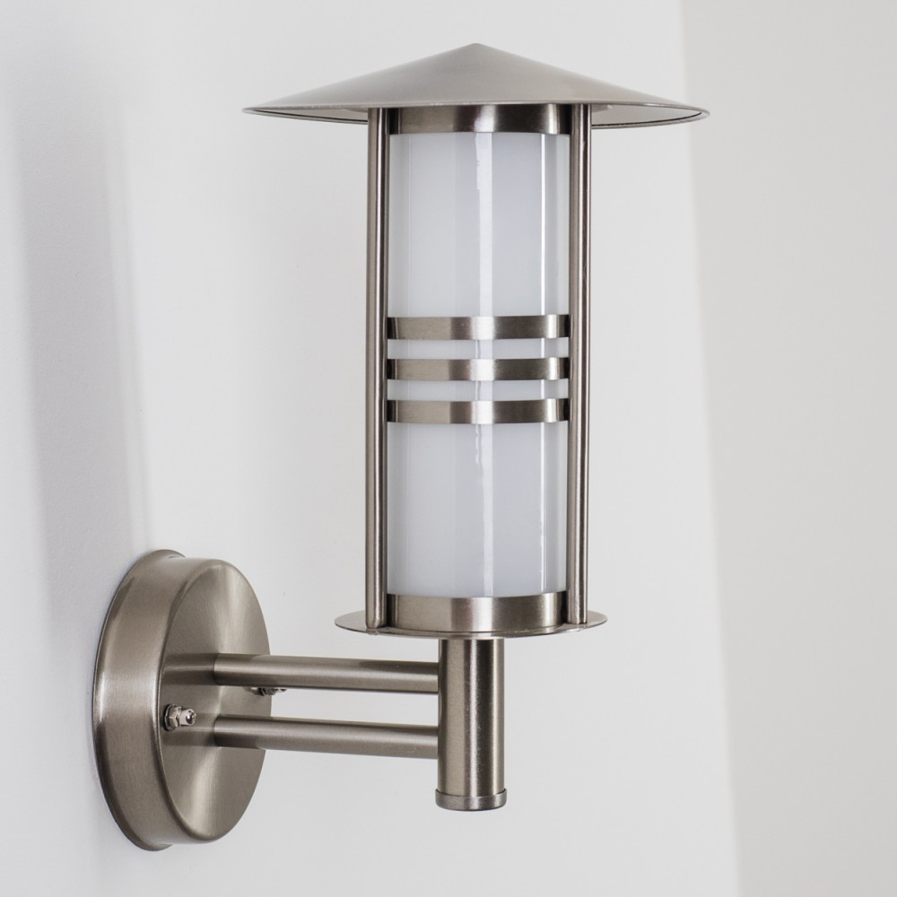 Eine Metall-Außenlampe ist an einer weißen Wand montiert. Die Lampe ist silberfarben mit einem zylindrischen Licht und einem flachen Dach, mit zwei horizontalen Bändern.