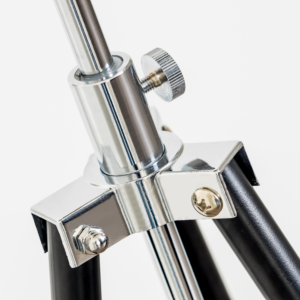 Nahaufnahme eines Chrom-Mikrofonständergelenks. Verfügt über eine glänzende Metallstruktur mit einer Schraube und schwarzen Beinen auf weißem Hintergrund.