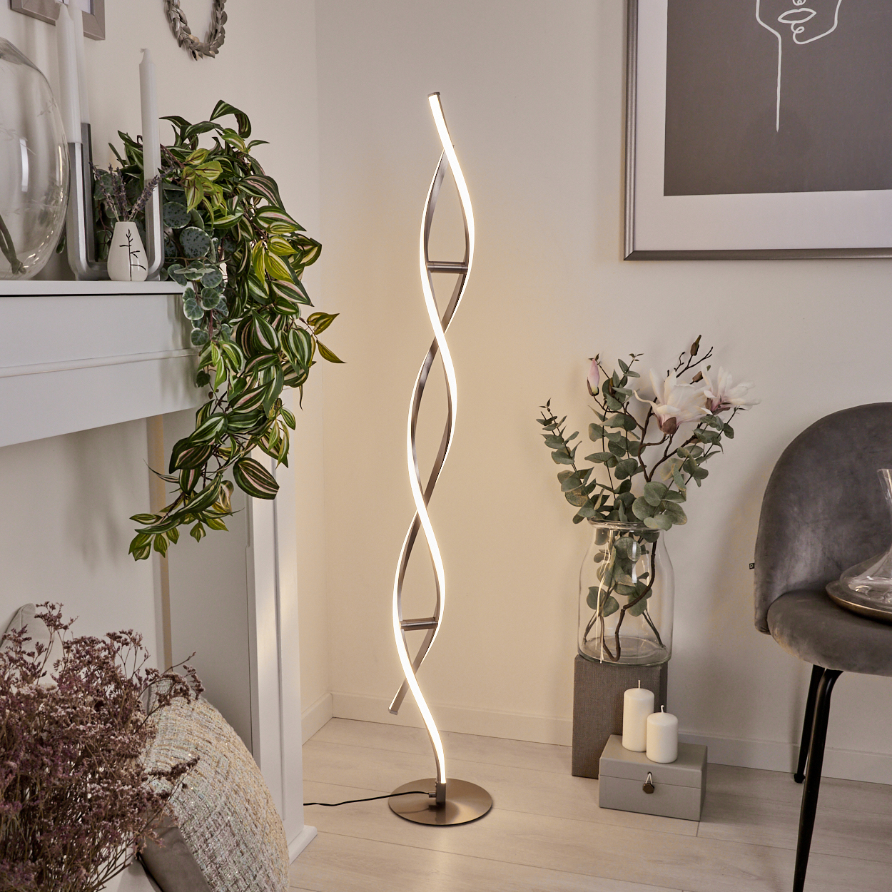 Ein modernes Wohnzimmer mit einer spiralförmigen LED-Stehlampe. Es gibt Pflanzen, Kerzen, eine Blumenvase und einen grauen Stuhl.