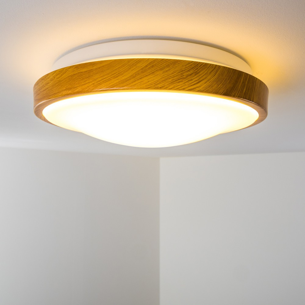 Eine Deckenleuchte. Sie hat einen Holzrahmen und eine weiße Basis. Das Licht ist hell.
