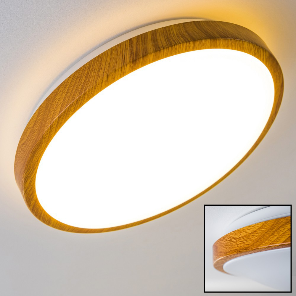 Eine moderne Deckenleuchte. Sie hat einen Holzrahmen und eine helle, weiße Lichtquelle. Der Hintergrund ist eine schlichte weiße Decke.