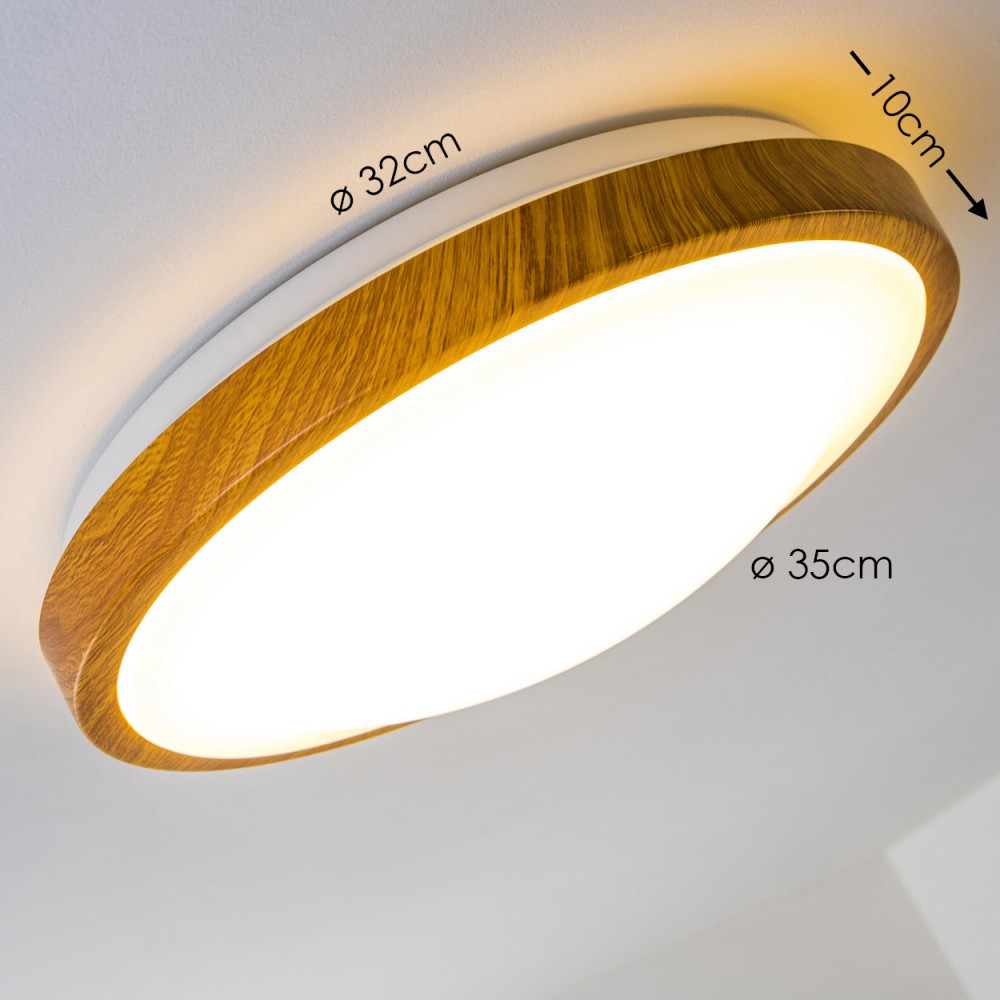 Eine runde Deckenlampe mit Holzoptik. Sie ist beleuchtet, mit den Abmessungen 32 cm und 35 cm Durchmesser. Die Decke ist weiß.