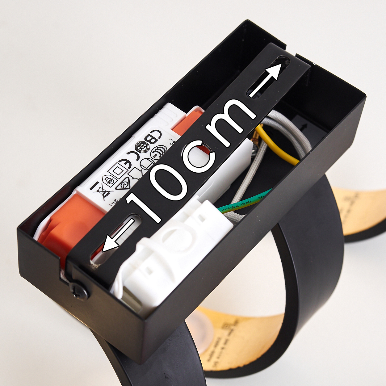 Schwarze Metallleuchte mit Innenteilen. Weiße und orangefarbene Elektronik, Drähte und ein 10 cm Maß sind sichtbar.