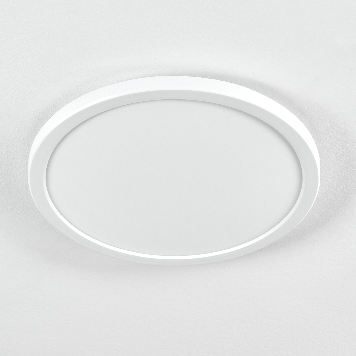 Eine weiße, ovale Deckenleuchte. Sie ist an einer weißen, strukturierten Decke montiert. Das Licht ist ausgeschaltet.