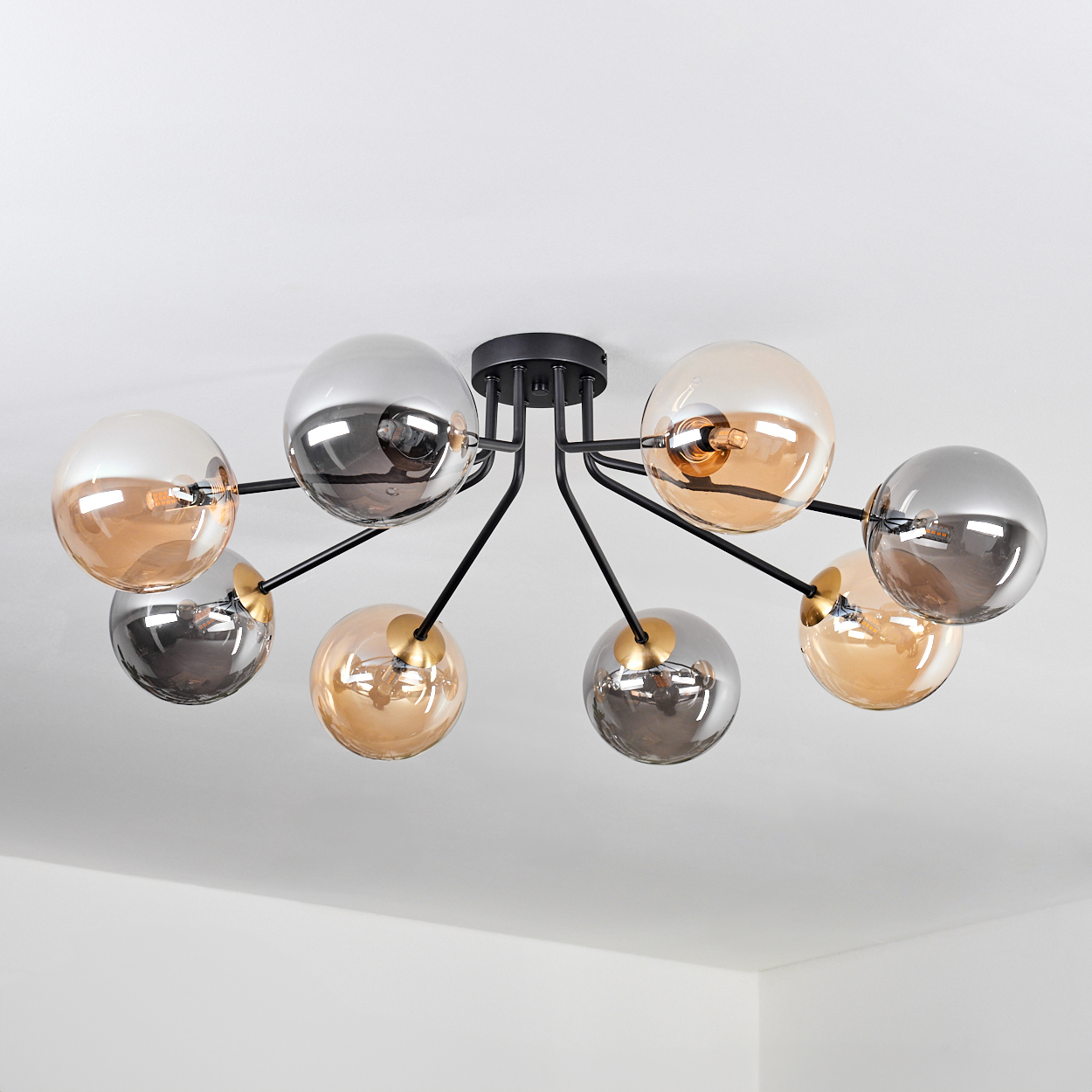 Eine moderne Deckenleuchte mit acht Glasglobus in Silber und Bernstein, befestigt an schwarzen Armen. Das Licht ist gegen eine weiße Decke.