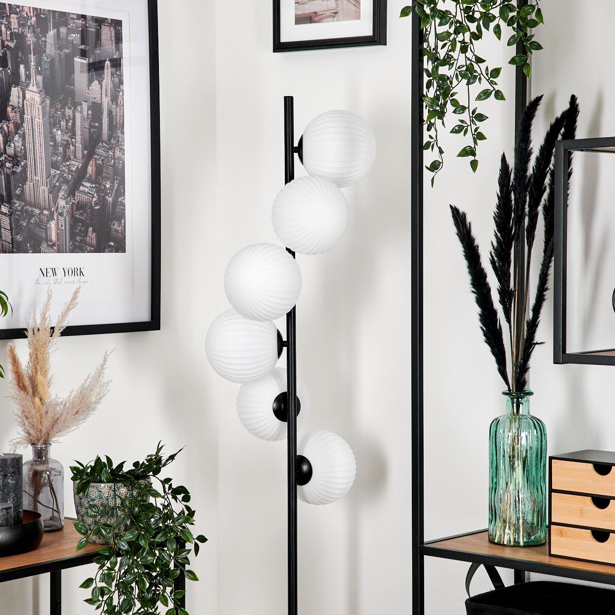 Ein modernes Wohnzimmer mit Stehlampe, New York-Kunst und dekorativen Pflanzen.