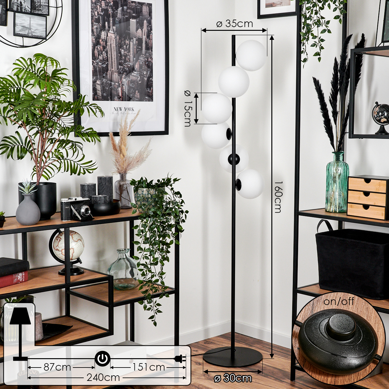 Eine schwarze Stehlampe mit weißen Kugelschirmen. Links ein Regal mit Dekorationen und einem New York-Bild. Ein-/Ausschalter auf dem Boden.