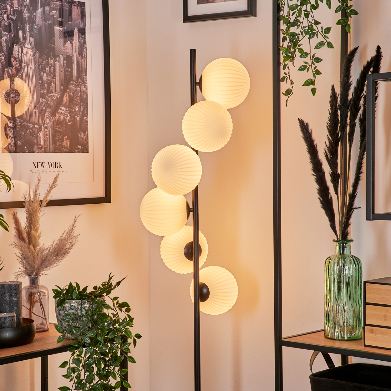 Eine moderne Stehlampe mit runden, leuchtenden Schirmen ist der Mittelpunkt. Pflanzen, Kunstwerke und Dekorationsgegenstände vervollständigen das stilvolle Interieur.