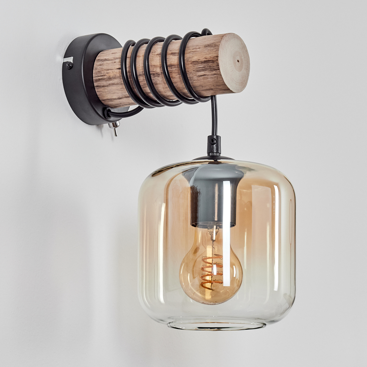 Eine Wandleuchte aus Holz und Metall mit Glasschirm und sichtbarer Glühbirne, montiert an einer weißen Wand.