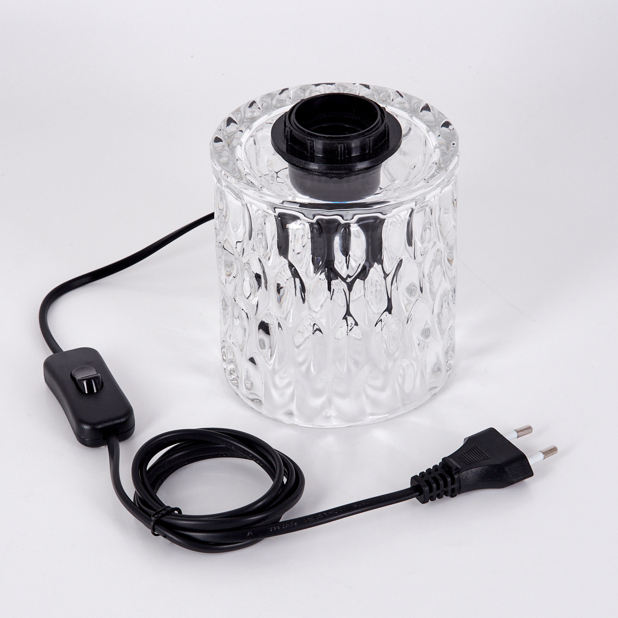 Ein klarer Glaslampensockel mit schwarzem Deckel, schwarzem Kabel und Stecker. Der Sockel hat eine strukturierte Oberfläche. Der Hintergrund ist weiß.