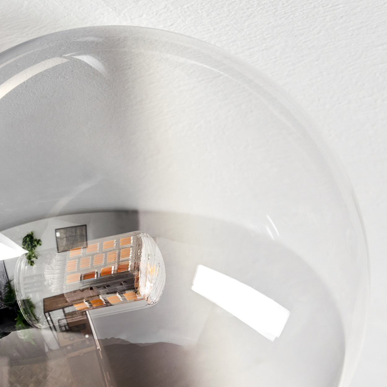 Eine klare Glühbirne mit einer LED-Leuchte im Inneren. Ein kleiner Raum spiegelt sich in der Birne. Der Hintergrund ist weiß.