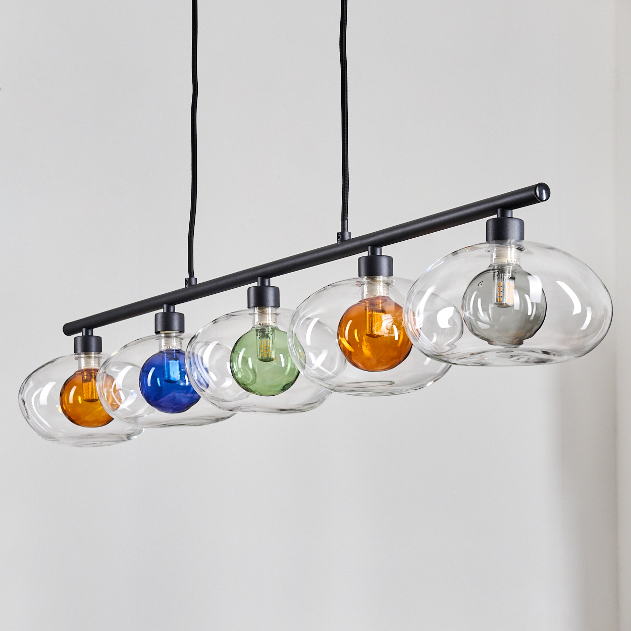 Eine moderne Hängelampe mit fünf Glaskolben. Jede Glühbirne hat eine andere Farbe: orange, blau, grün, orange und grau.