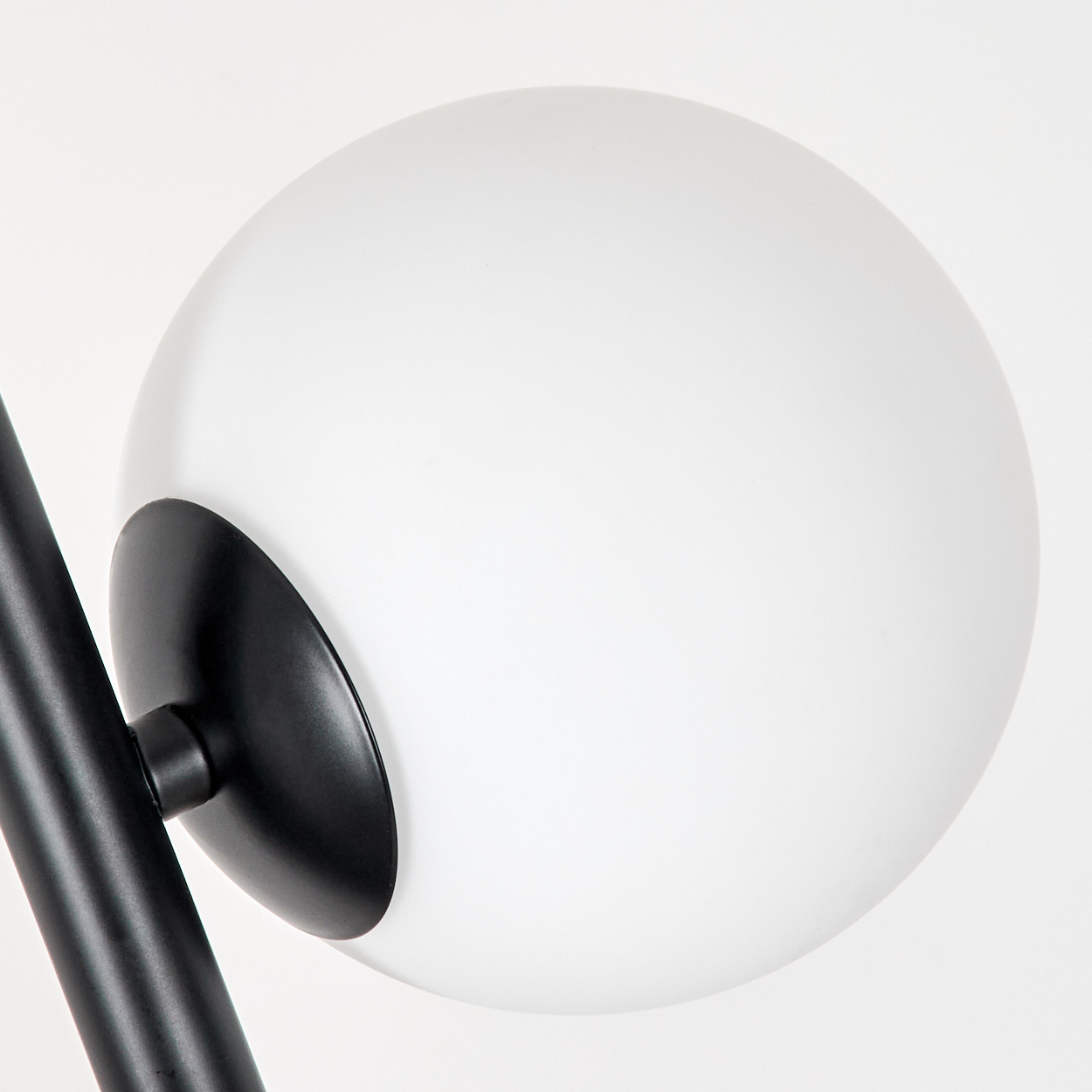 Eine moderne Lampe mit weißem Globus und schwarzem Metallträger auf weißem Hintergrund. Die Lampe ist ausgeschaltet.