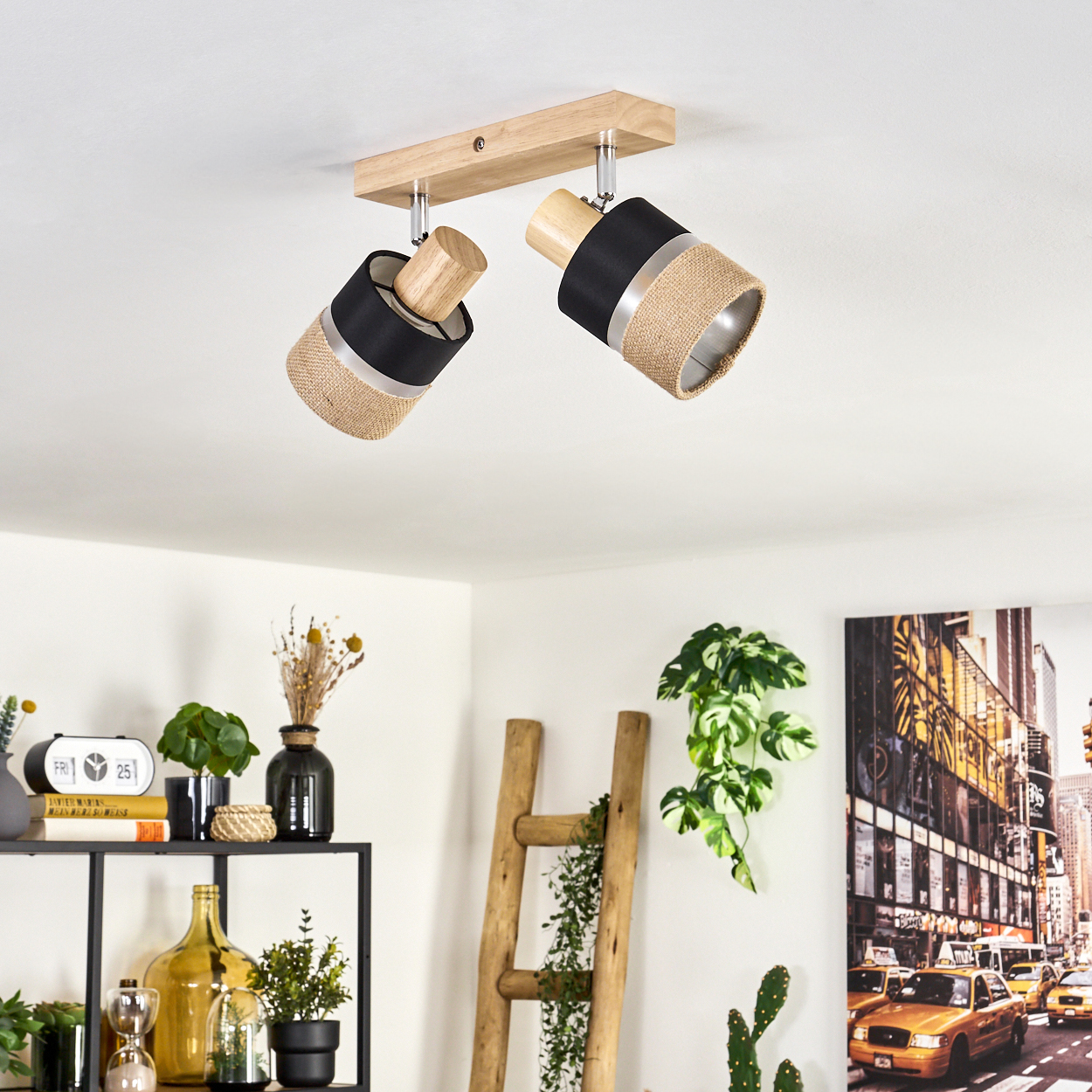 Deckenleuchte mit zwei Lampen. Die Lampen haben schwarze, beige und silberne Schirme. Im Hintergrund ein Regal mit Dekoration und eine Leiter.