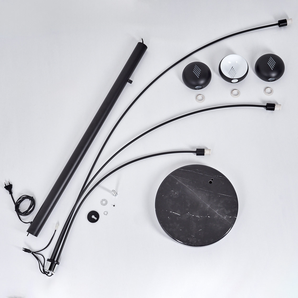 Zerlegte schwarze Stehlampe auf weißem Untergrund. Komponenten: Sockel, gebogene Arme, Lampenköpfe, Mittelstange, Hardware.