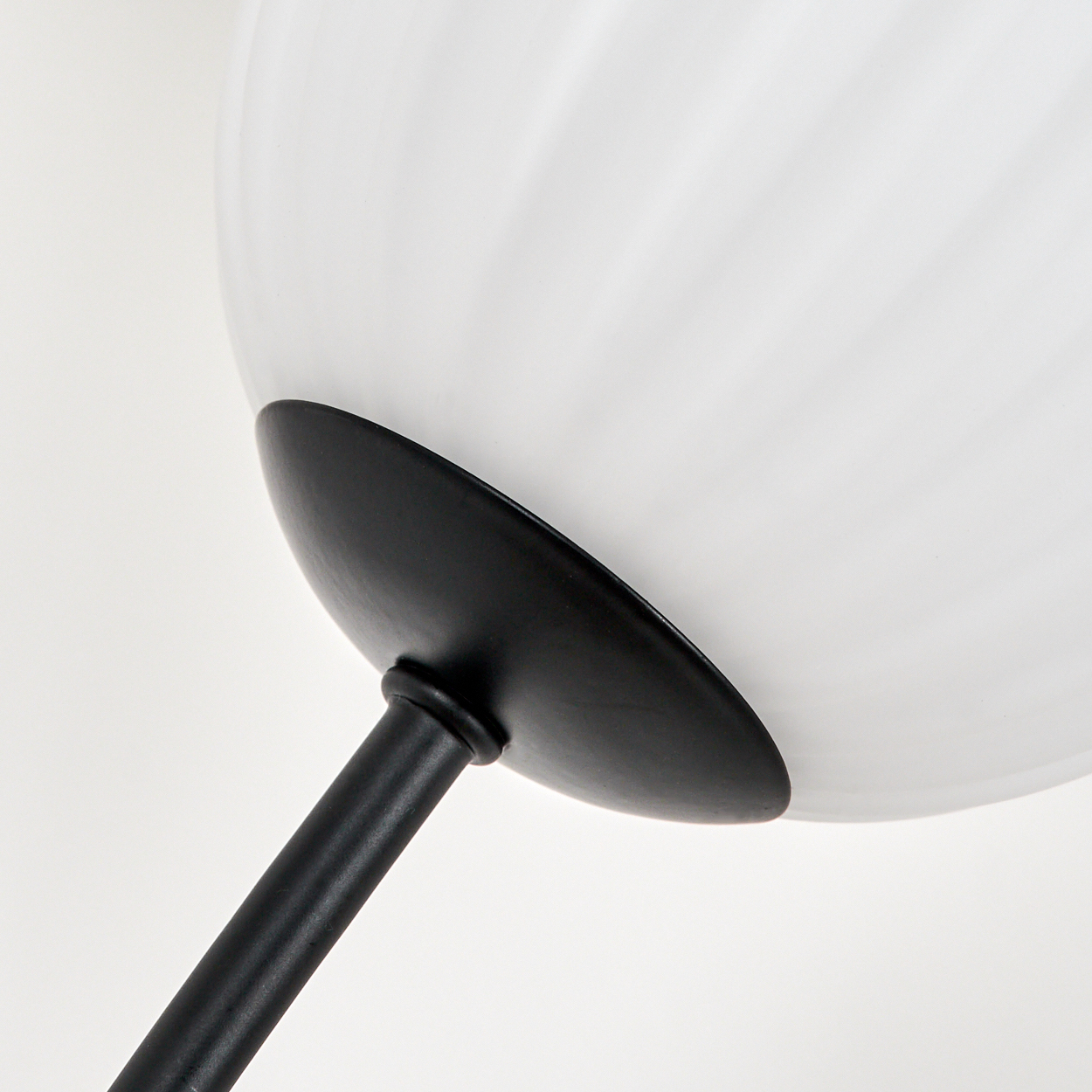 Nahaufnahme einer Lampe. Weißer Glaskolben mit schwarzem Metallschaft und rundem Sockel. Weißer Hintergrund.