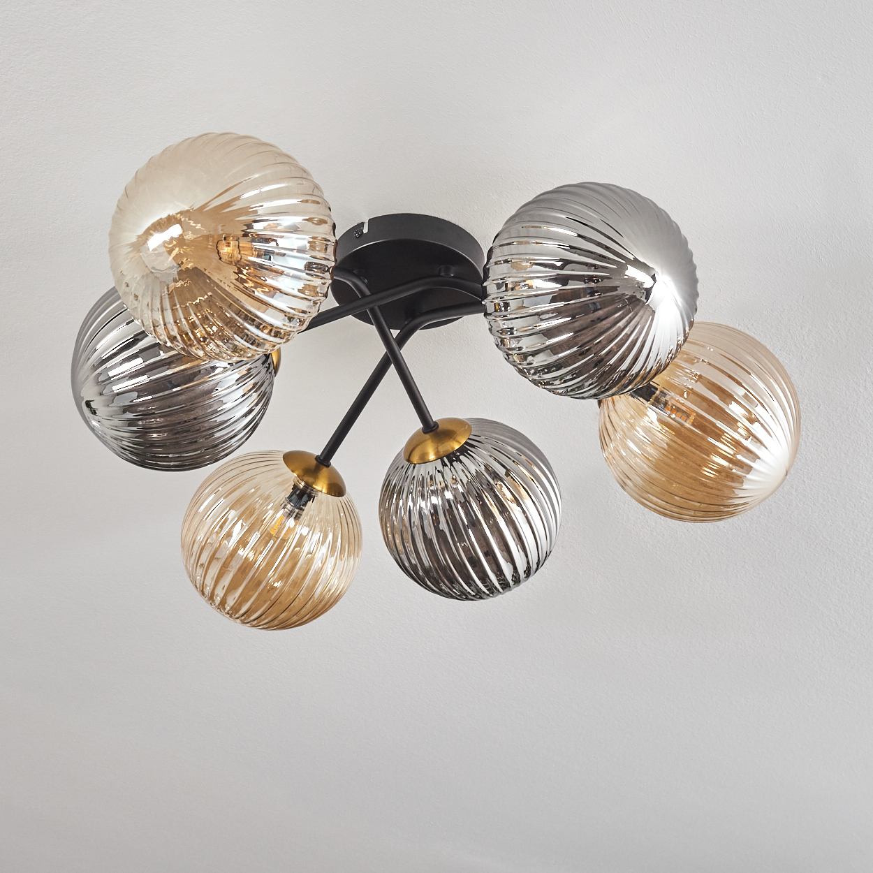 Eine moderne Deckenleuchte mit sechs kugelförmigen Glasschirmen in Silber und Gold, befestigt an einem schwarzen Metallrahmen an einer weißen Decke.