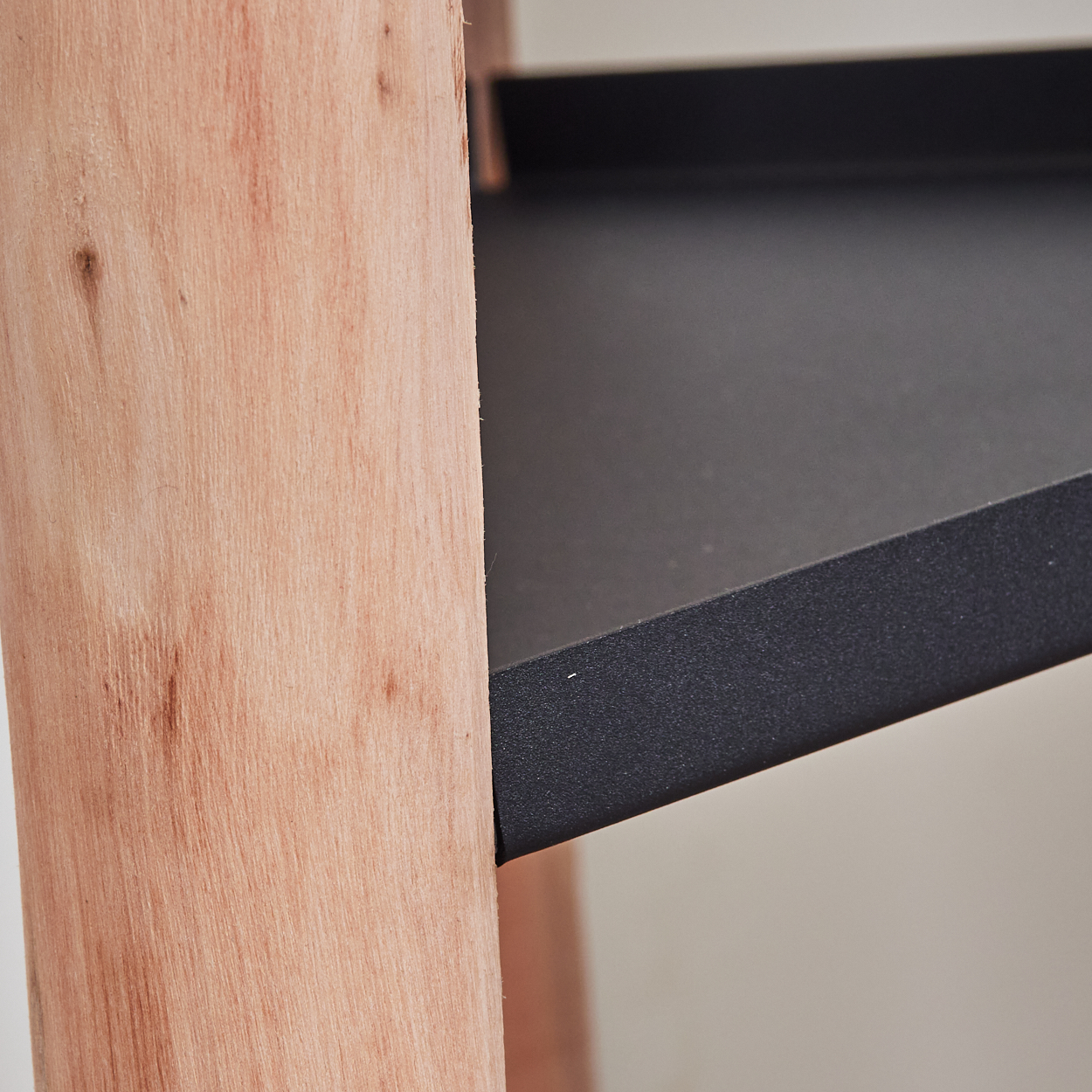 Nahaufnahme einer Holzstruktur mit einem schwarzen Regal. Das Holz ist hellbraun und das Regal rechteckig.