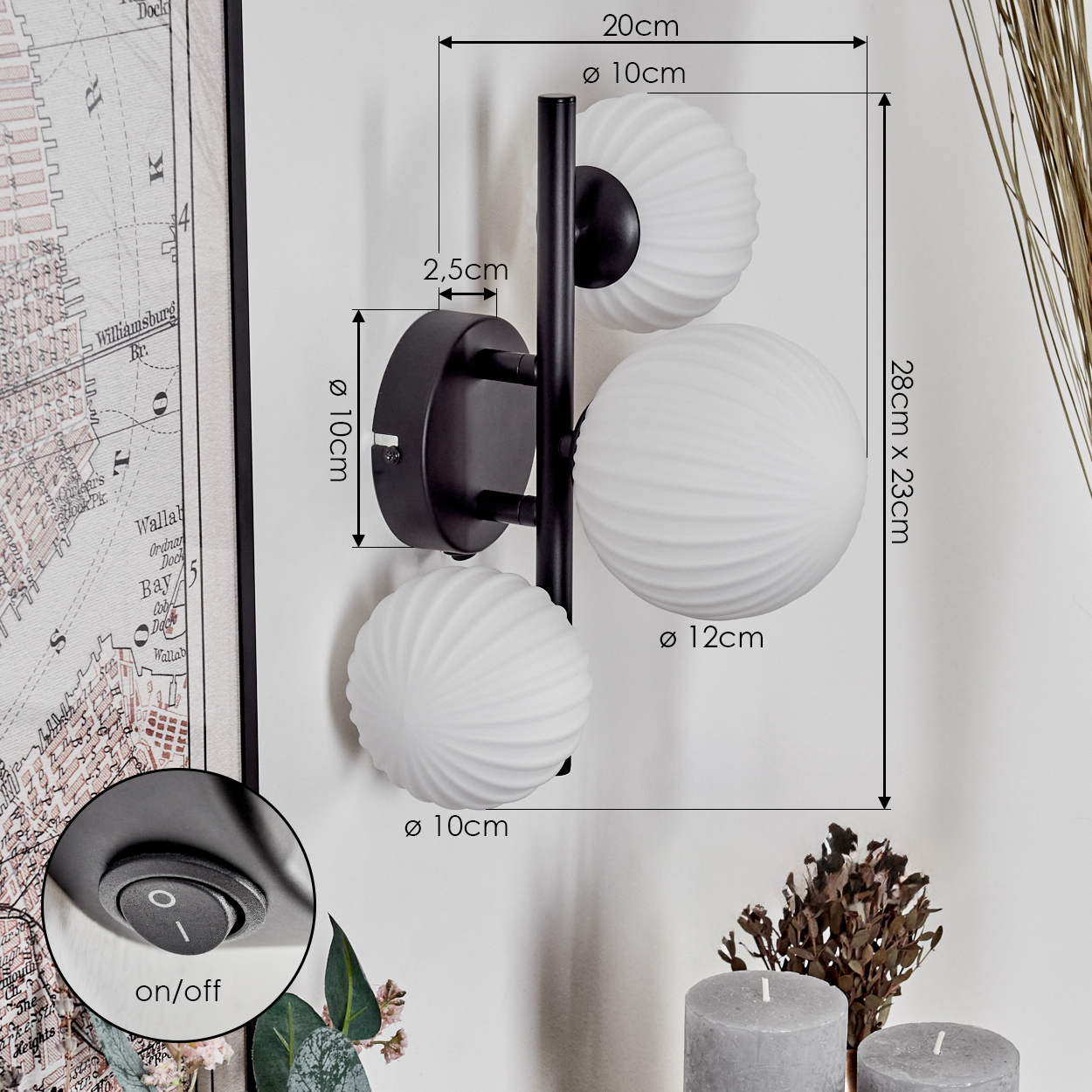 Eine schwarze Wandlampe mit drei weißen Kugelleuchten ist an einer weißen Wand montiert. Abmessungen sind angegeben. Ein Ein/Aus-Schalter ist ebenfalls sichtbar.