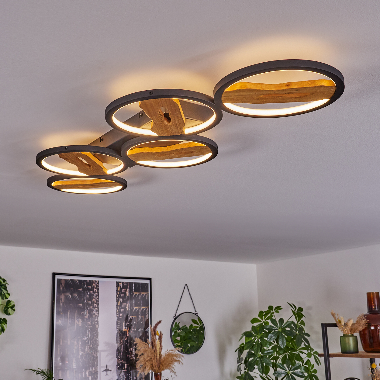 Eine Deckenleuchte mit sechs kreisförmigen Lichtern, jeweils mit einem Holzmittelstück. Die Lichter sind bogenförmig an der Decke angeordnet.