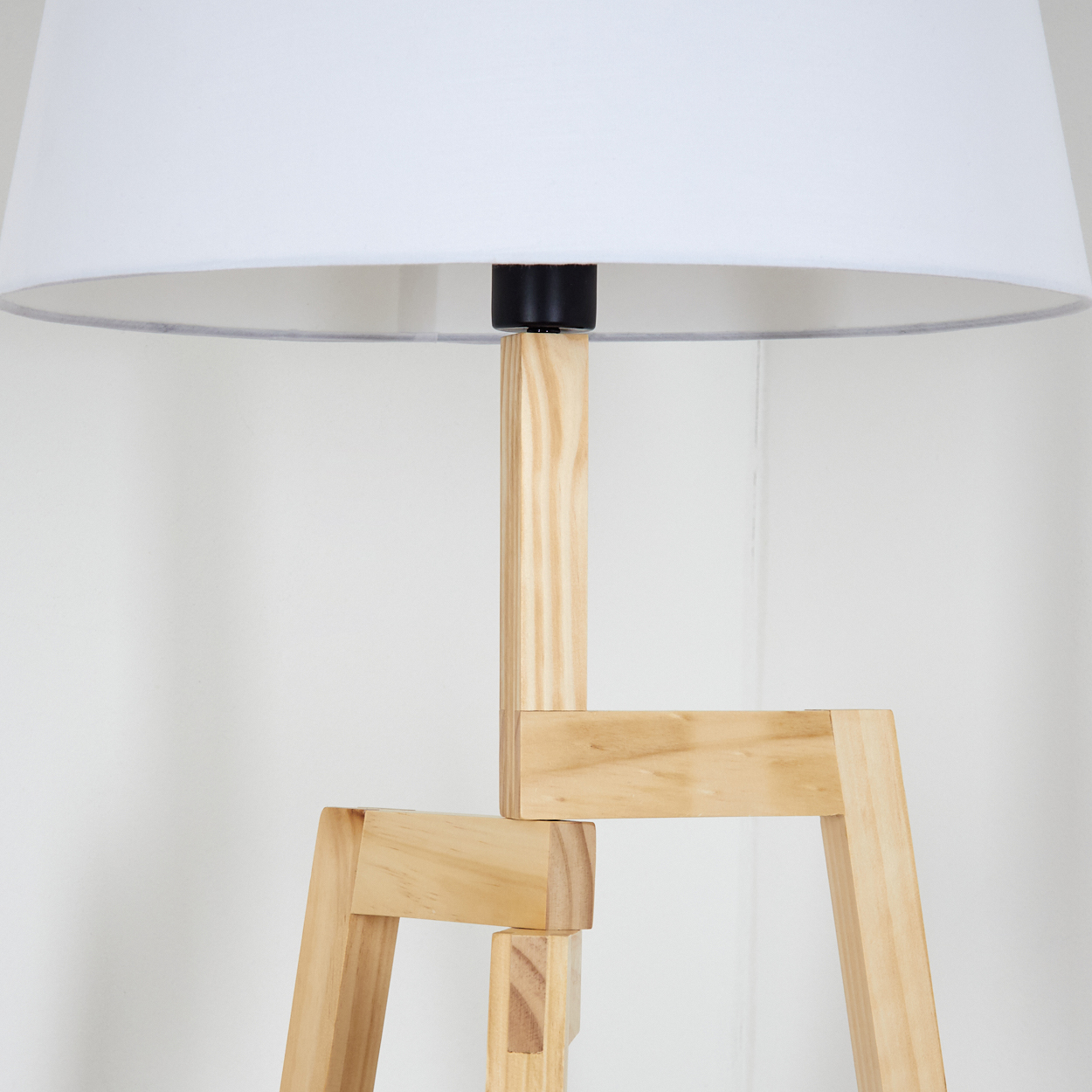 Eine Stehlampe aus Holz mit weißem Lampenschirm. Der Sockel besteht aus hellem Holz und ist in einem interessanten geometrischen Design angeordnet.