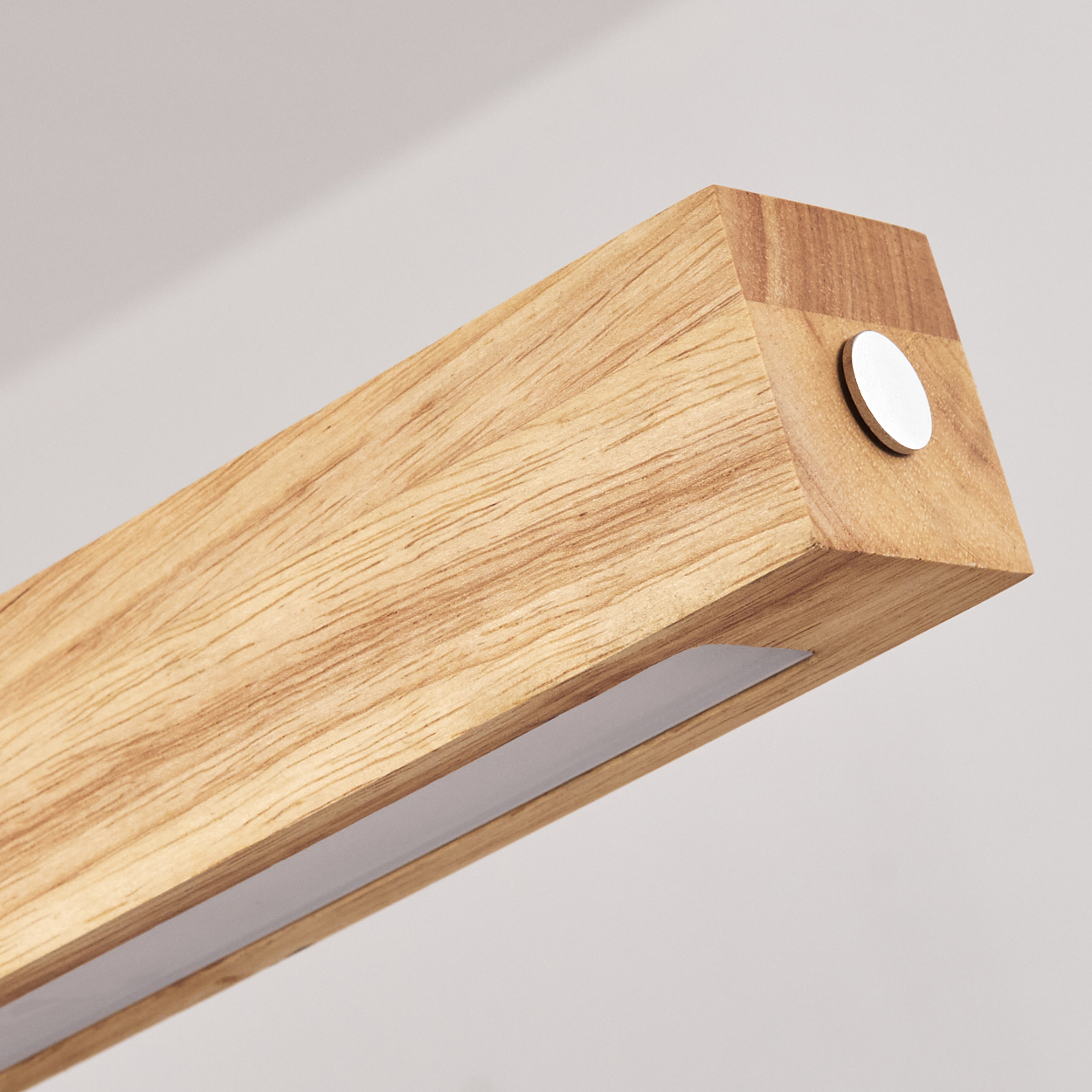 Holzlichtleuchte mit weißem Lichtstreifen. Es hat eine kleine Metallscheibe. Der Hintergrund ist ein schlichtes Weiß.