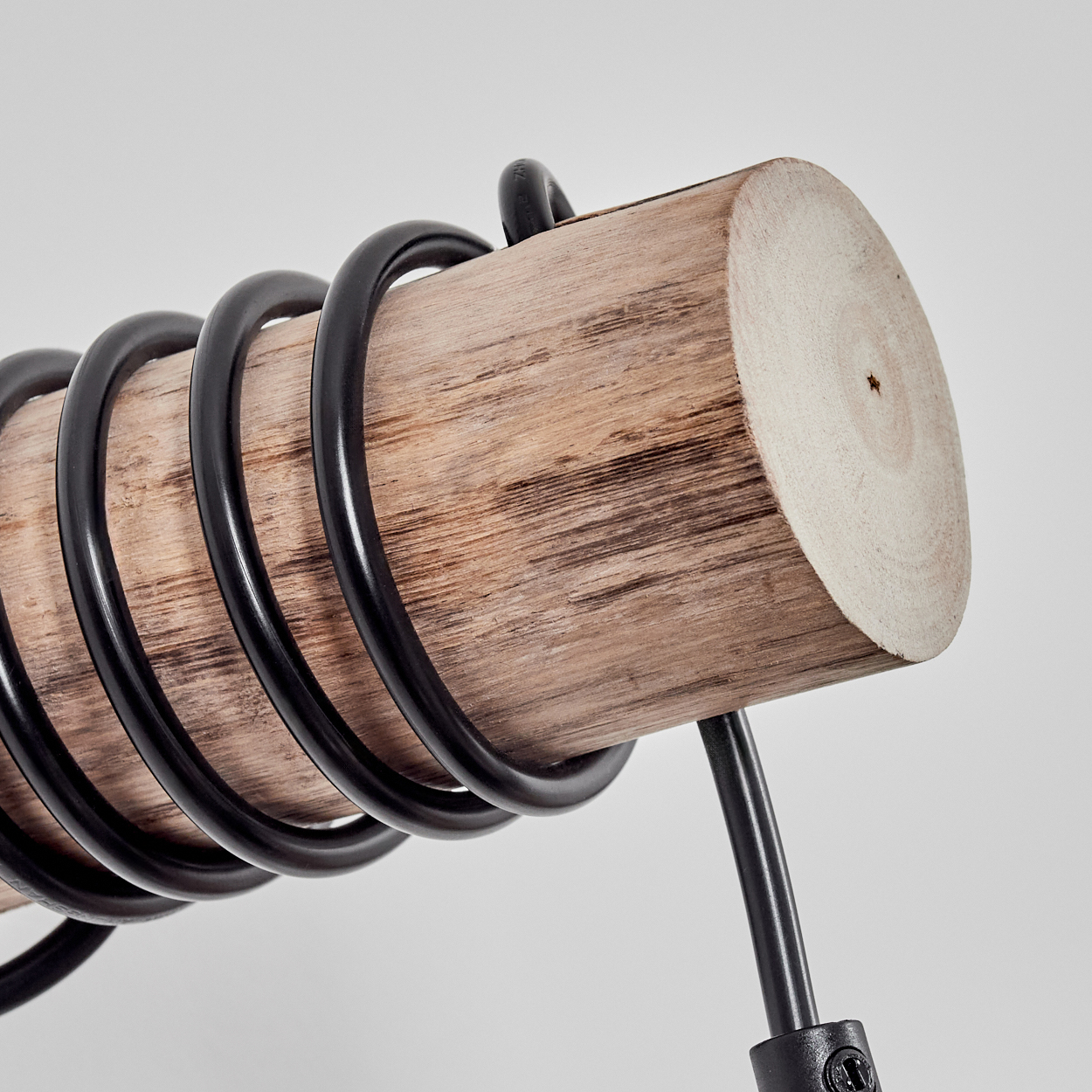 Ein Holzstamm mit schwarzen Metallringen. Er liegt vor einem weißen Hintergrund. Ein schwarzer Metallschaft ist befestigt.