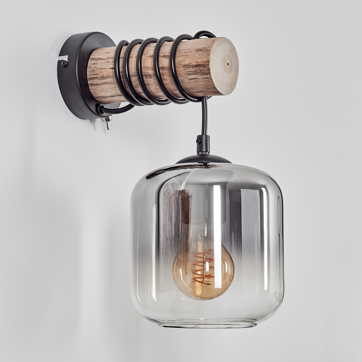 Eine Wandlampe mit Holzbalken, spiralförmigen Metallspulen und einem Glasschirm, der eine leuchtende Glühbirne beherbergt.