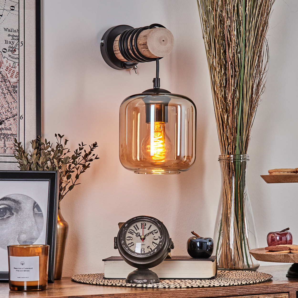 An der Wand hängt eine Lampe mit Glasschirm und leuchtender Glühbirne. Weitere Objekte sind eine Uhr, eine Vase mit Pflanzen und ein Bilderrahmen.