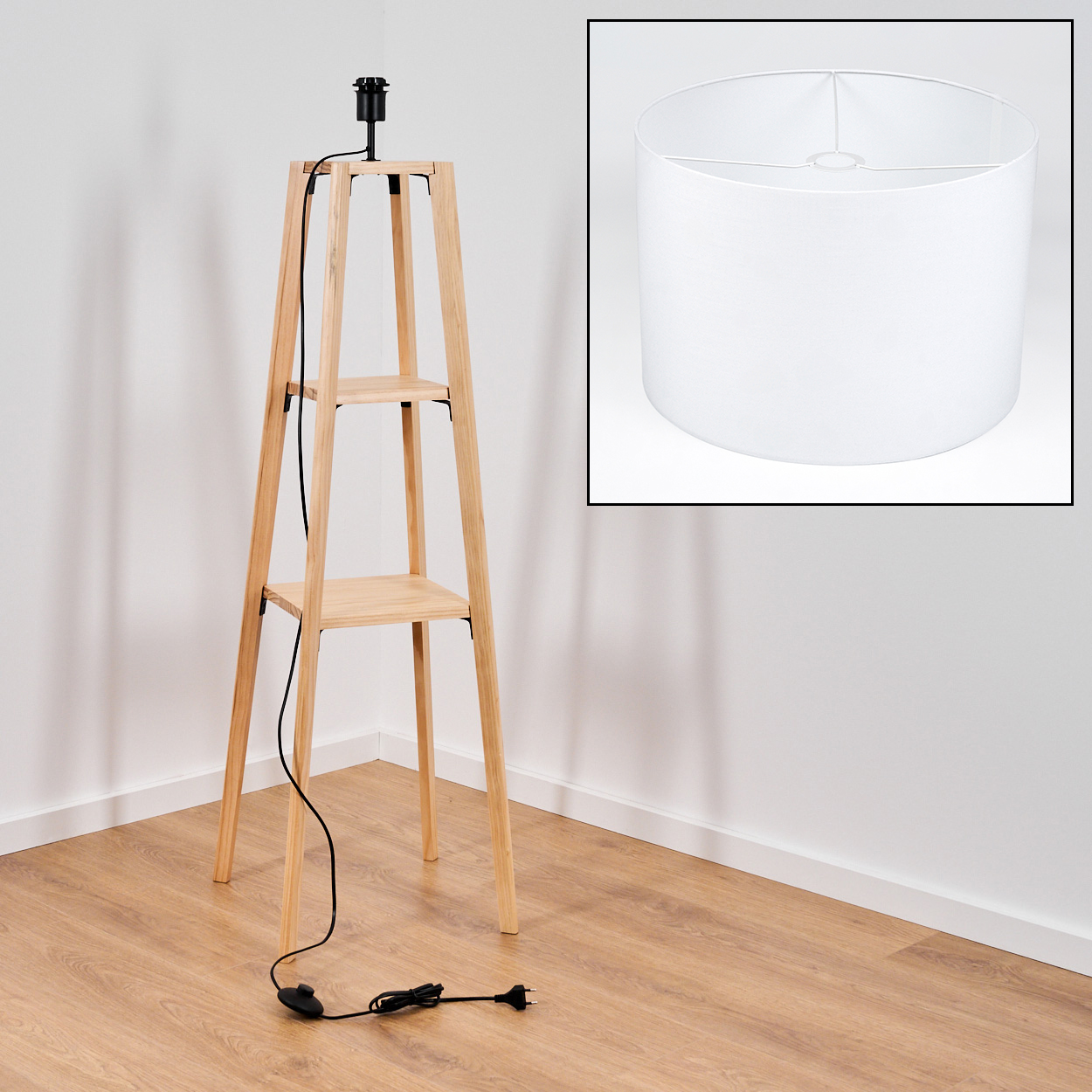 Eine Holzlampe mit schwarzem Kabel und Stecker. Ein weißer Lampenschirm befindet sich in einer separaten Box. Die Lampe hat zwei Regale.