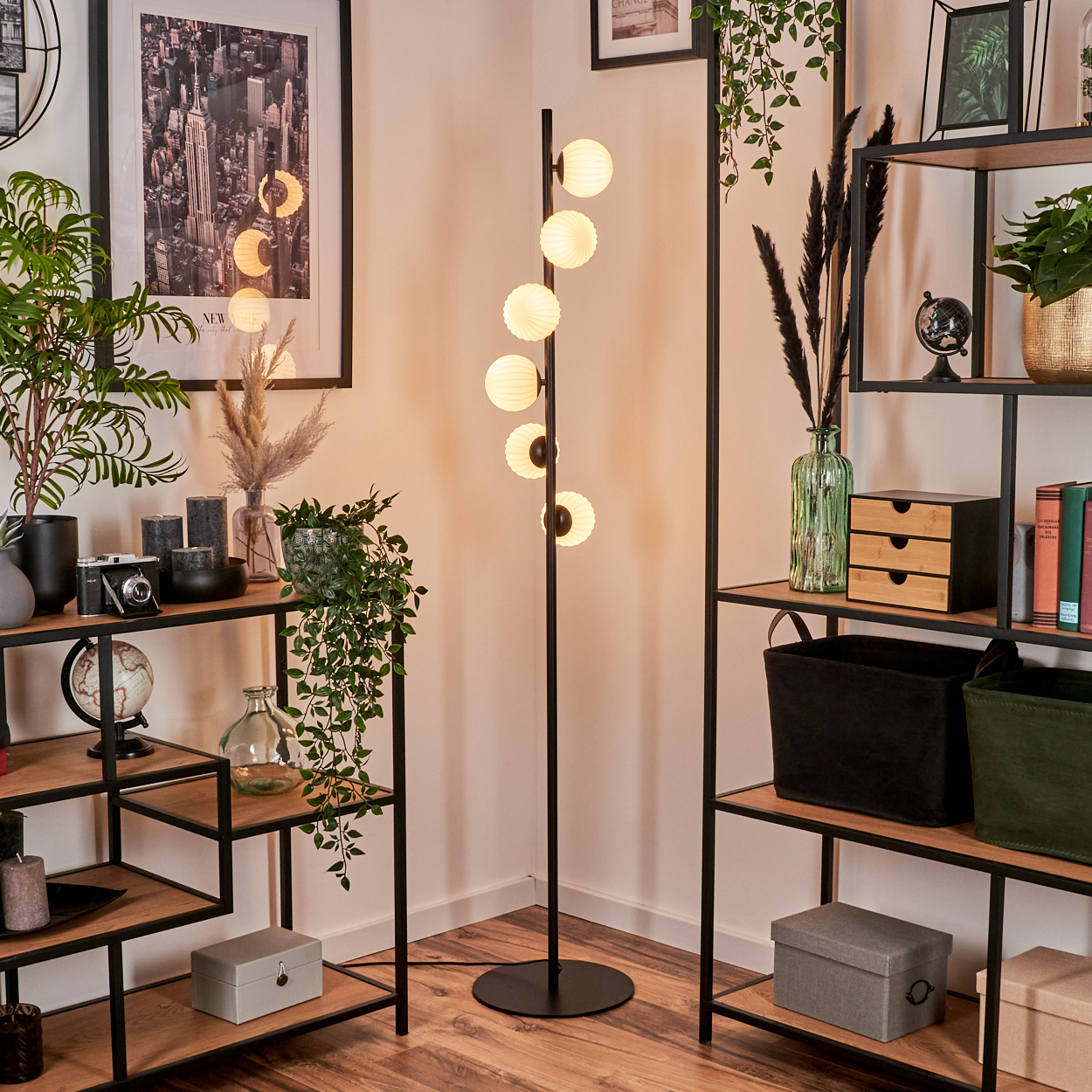 Ein modernes Zimmer mit Stehlampe. Regale zeigen Pflanzen, Deko und ein Foto. Die Lampe hat runde, leuchtende Lichter.