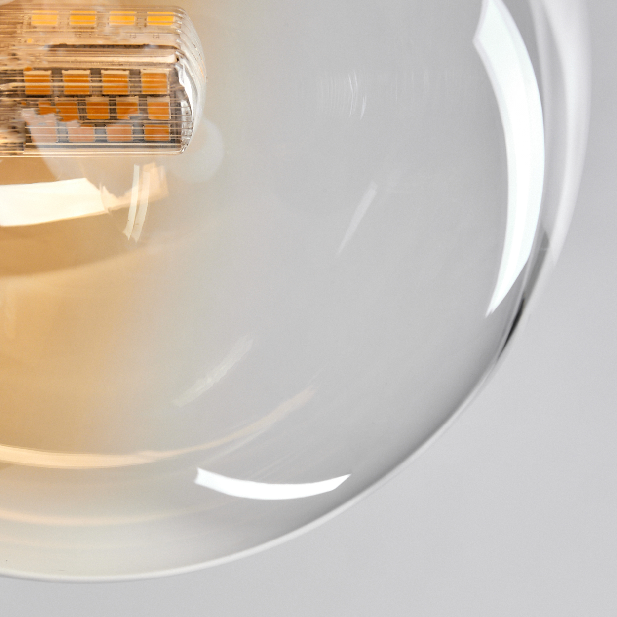 Nahaufnahme einer modernen Leuchte. Ein transparenter Glaskolben umgibt eine Glühbirne mit sichtbaren orangefarbenen LEDs.