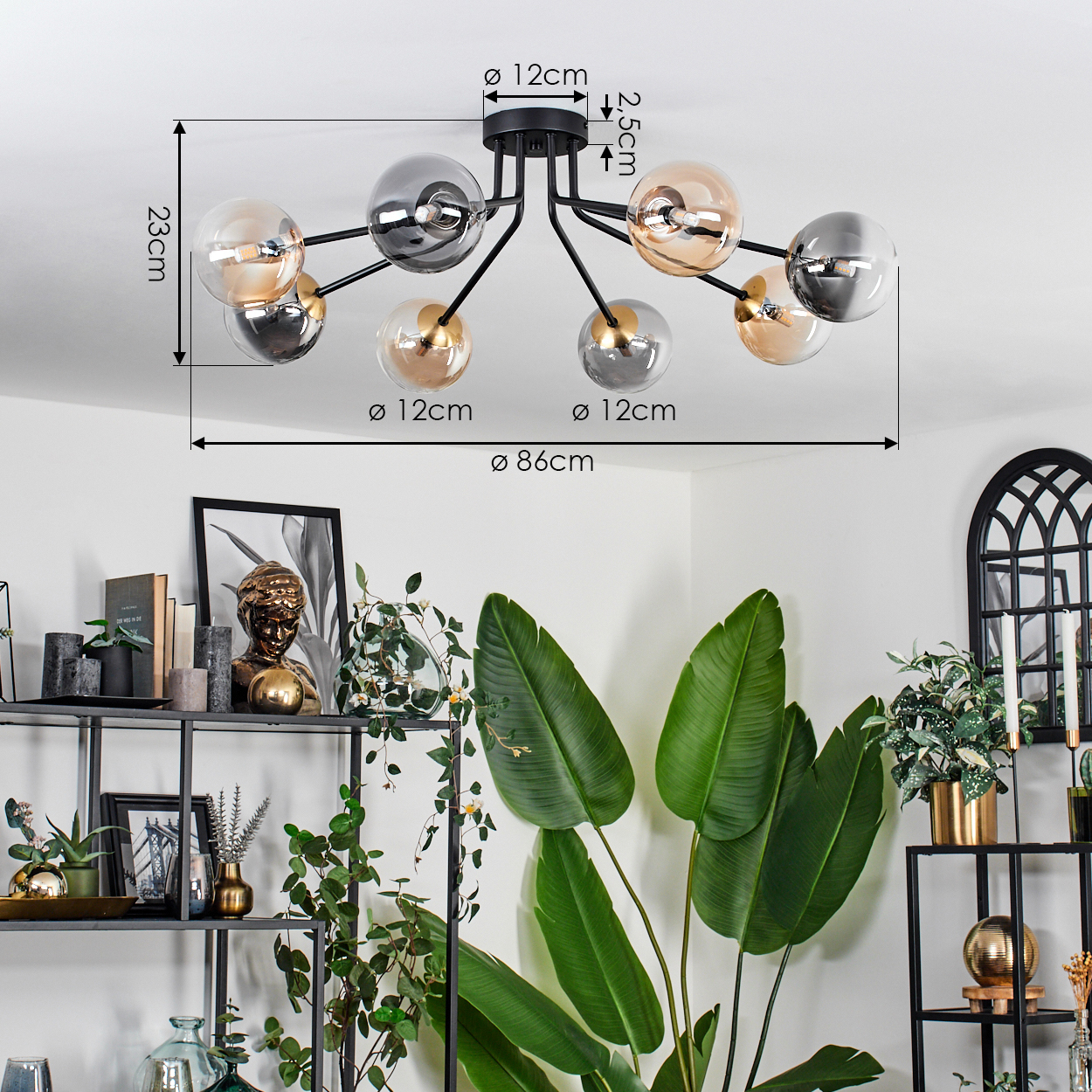 Eine moderne Deckenlampe mit Glaskugeln und einem schwarzen Metallrahmen. Darunter grüne Pflanzen und Regale mit Dekoration.