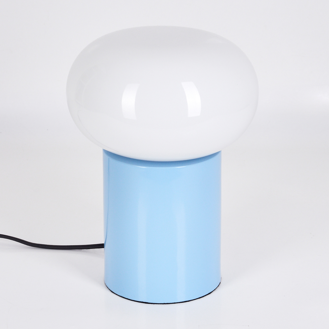 Eine moderne Lampe mit weißem, rundem Oberteil und hellblauem zylindrischen Sockel, vor weißem Hintergrund. Ein schwarzes Kabel geht von der Basis aus.
