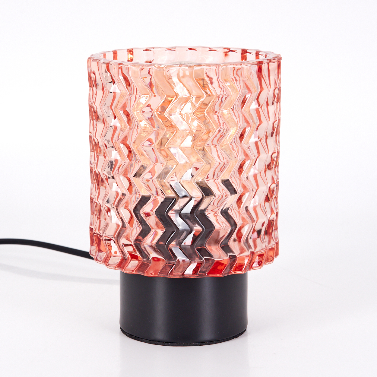 Eine dekorative Tischlampe. Sie hat einen rosa, gemusterten Glasschirm auf einem schwarzen Sockel. Ein schwarzes Kabel erstreckt sich vom Sockel.